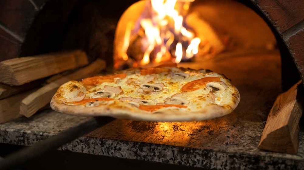 Cuisson d'une pizza dans un four à bois traditionnel